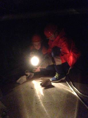 Zwei Jugendfeuerwehrmitglieder suchen im Dunkeln den Raum mit Hilfe einer Lampe ab